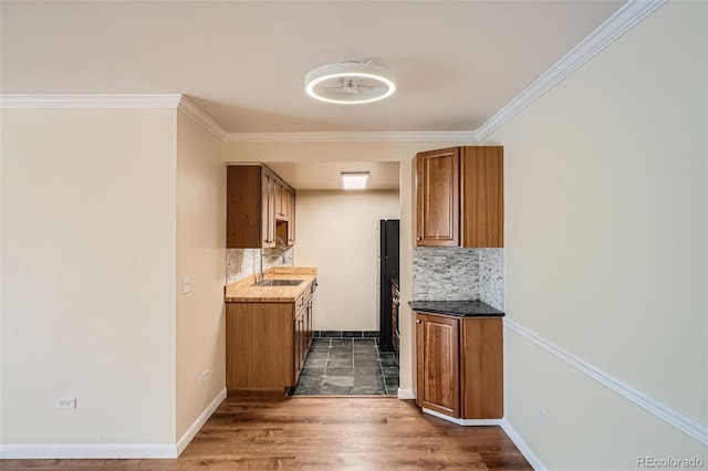 kitchen featuring ornamental molding, backsplash, dark hardwood / wood-style floors, and black fridge