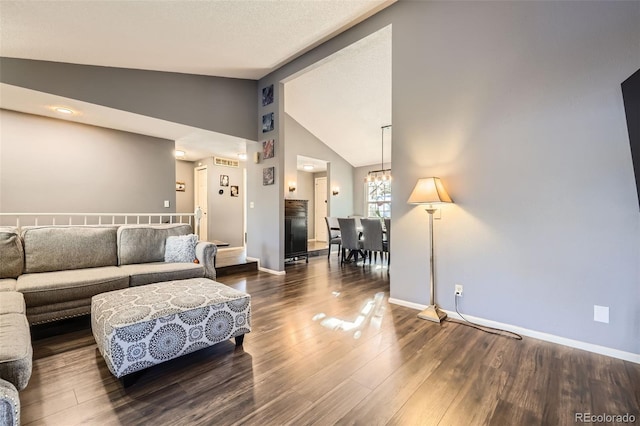 living room featuring dark hardwood / wood-style flooring, vaulted ceiling, and an inviting chandelier