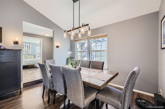 dining space with a textured ceiling, vaulted ceiling, and wood-type flooring