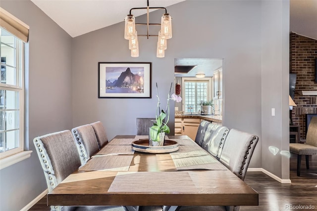 dining room featuring vaulted ceiling, a brick fireplace, and dark hardwood / wood-style flooring