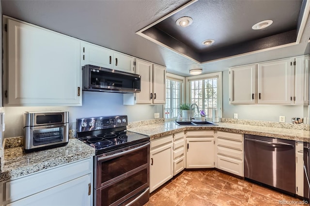 kitchen featuring a raised ceiling, appliances with stainless steel finishes, sink, and white cabinets