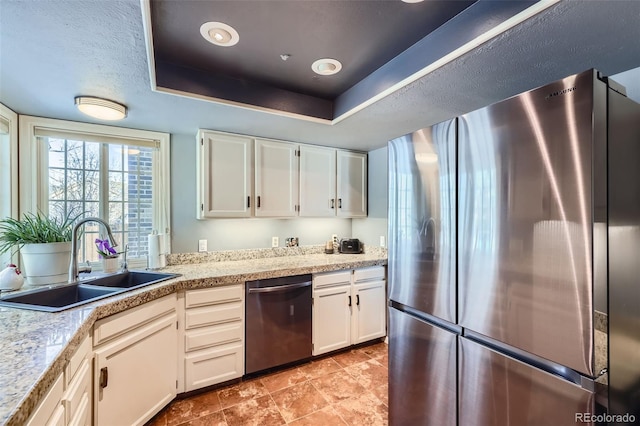 kitchen with sink, stainless steel appliances, a raised ceiling, and white cabinets