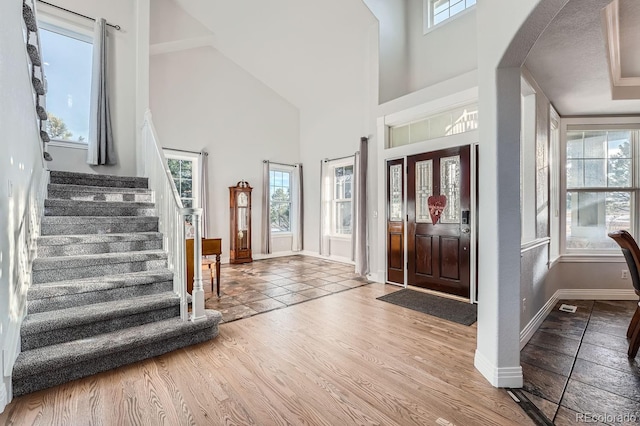 foyer with wood-type flooring and high vaulted ceiling