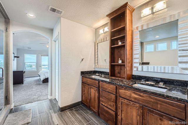 bathroom with walk in shower, ceiling fan, vanity, and a textured ceiling