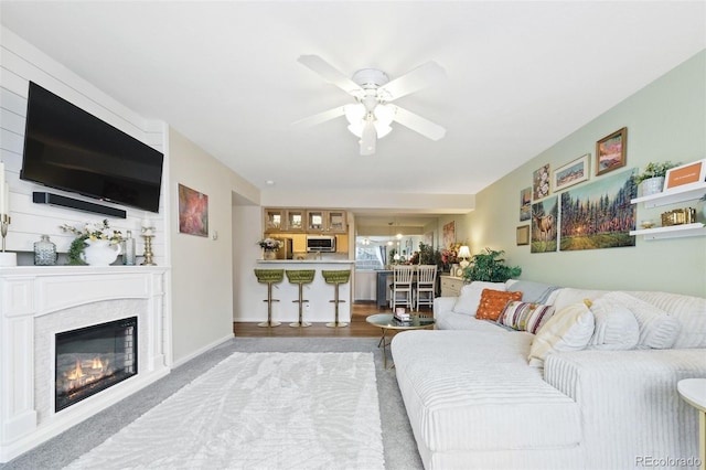 living area featuring ceiling fan, a premium fireplace, and baseboards