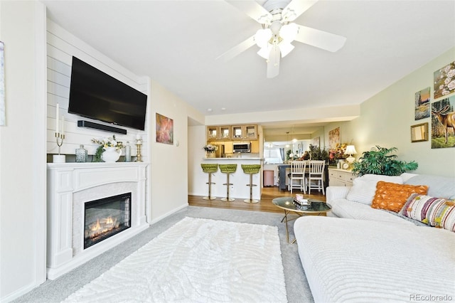 bedroom with light wood finished floors, a glass covered fireplace, and baseboards