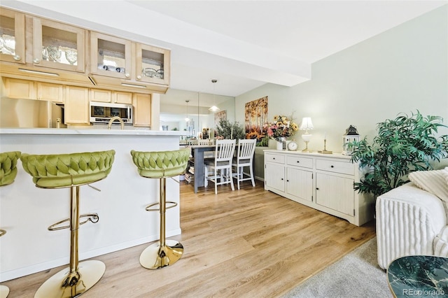 kitchen featuring glass insert cabinets, stainless steel appliances, light countertops, and light wood-style flooring