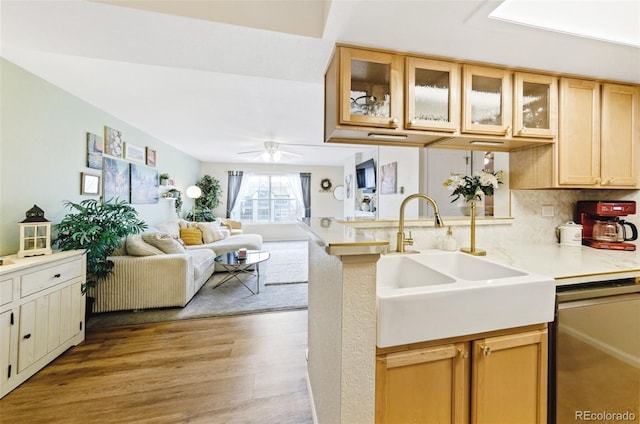 kitchen featuring light countertops, glass insert cabinets, open floor plan, a sink, and dishwasher