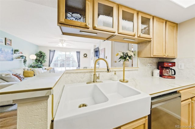 kitchen featuring dishwasher, glass insert cabinets, a peninsula, light countertops, and a sink