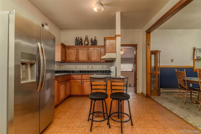 kitchen featuring light parquet floors, stainless steel refrigerator with ice dispenser, a kitchen island, and a breakfast bar