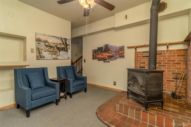 living area featuring carpet, ceiling fan, and a wood stove