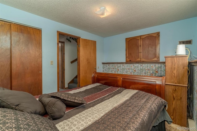 carpeted bedroom with a textured ceiling and a closet