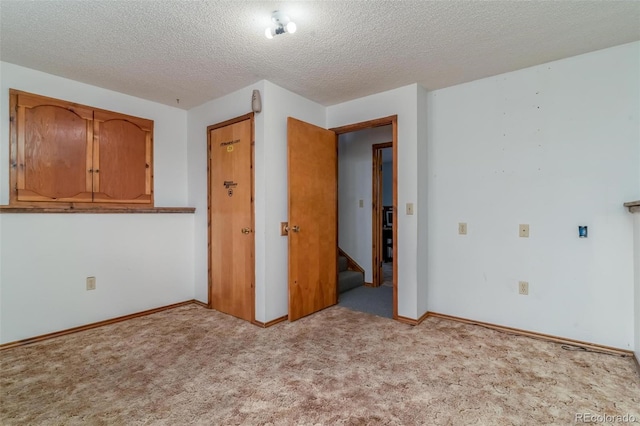 unfurnished room featuring a textured ceiling and light colored carpet