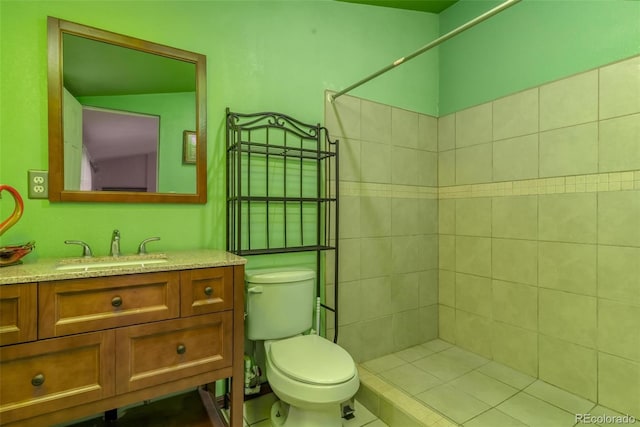 bathroom with tile patterned floors, tiled shower, vanity, and toilet