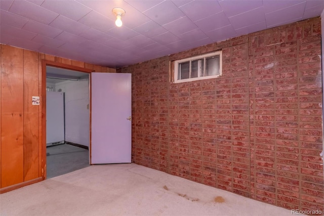 basement featuring carpet floors, wood walls, and white fridge