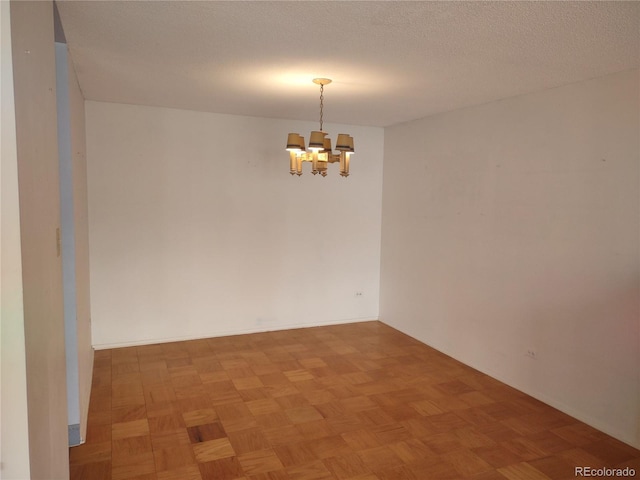 unfurnished room featuring parquet flooring, a textured ceiling, and a chandelier