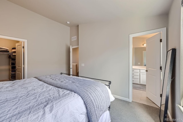 carpeted bedroom featuring a walk in closet, ensuite bathroom, and a closet