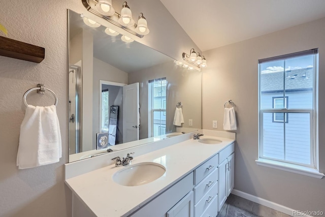 bathroom with a healthy amount of sunlight, vaulted ceiling, and vanity