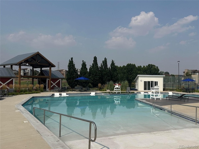 community pool featuring an outbuilding, a patio, and fence