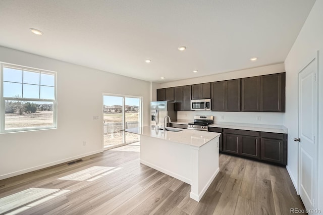 kitchen with light wood-style floors, visible vents, a center island with sink, and appliances with stainless steel finishes