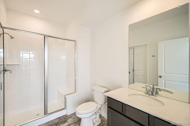 bathroom with vanity, a shower stall, toilet, and baseboards