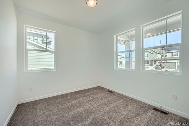 empty room featuring carpet flooring, visible vents, and baseboards