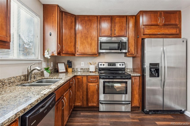 kitchen with light stone countertops, stainless steel appliances, dark hardwood / wood-style floors, and sink