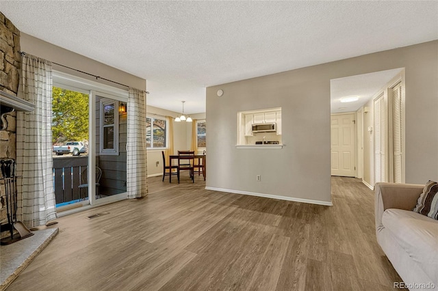 living room featuring an inviting chandelier, a textured ceiling, and light hardwood / wood-style floors