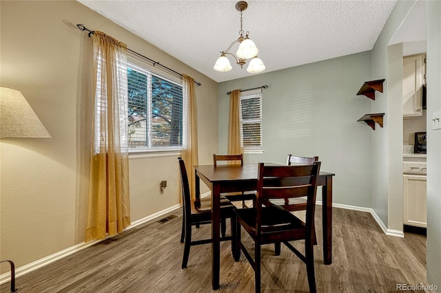 dining space featuring hardwood / wood-style floors, a notable chandelier, and a textured ceiling