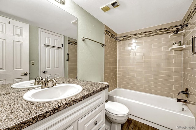 full bathroom featuring hardwood / wood-style flooring, vanity, tiled shower / bath, and toilet