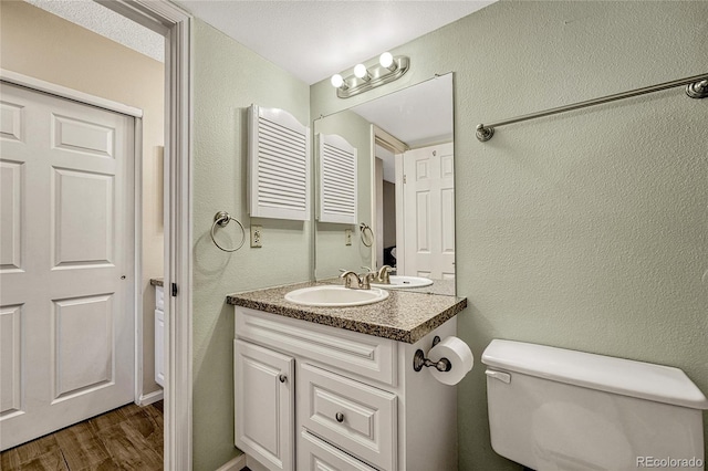 bathroom with vanity, toilet, and hardwood / wood-style floors