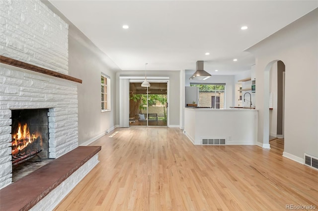 1579 Fairfax St, Denver, CO 80220 - unfurnished living room with light wood-type flooring, a stone fireplace, arched walkways, and recessed lighting
