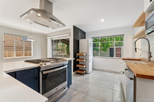 1579 Fairfax St, Denver, CO 80220 - kitchen featuring stainless steel appliances, ventilation hood, wood counters, decorative light fixtures, and recessed lighting