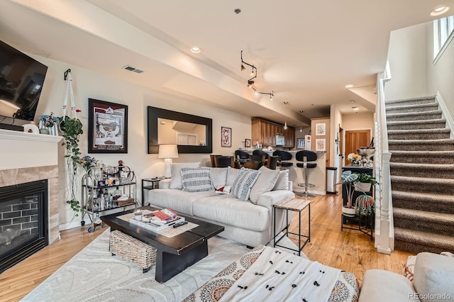 3030 Wyandot St Unit 7, Denver, CO 80211 - living room featuring stairway, light wood-type flooring, a tiled fireplace, track lighting, and recessed lighting