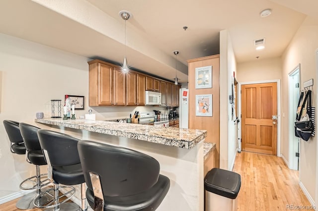 3030 Wyandot St Unit 7, Denver, CO 80211 - kitchen with white appliances, light wood finished floors, a kitchen breakfast bar, a peninsula, and light countertops