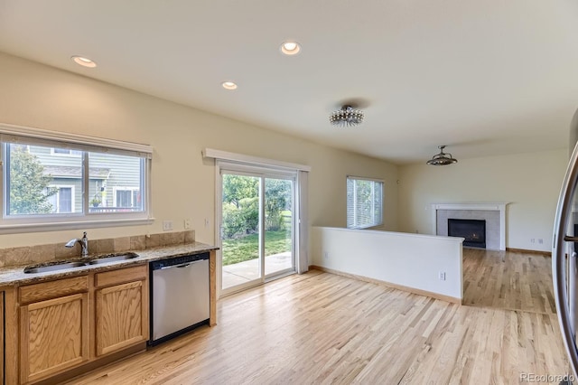 kitchen featuring light hardwood / wood-style flooring, dishwasher, a fireplace, and sink