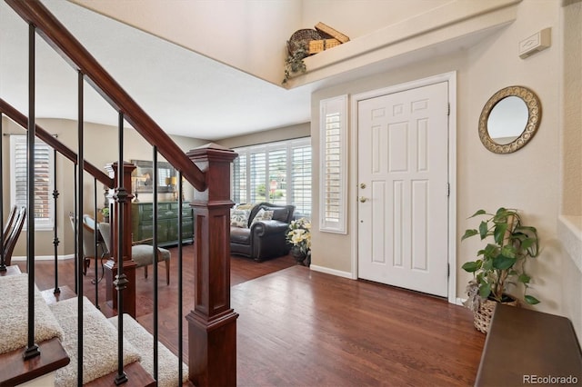 foyer entrance featuring stairway, baseboards, and wood finished floors