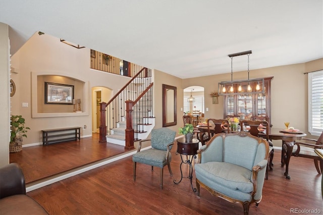 interior space featuring arched walkways, wood finished floors, stairway, baseboards, and a chandelier