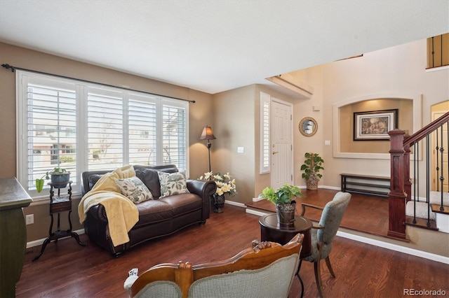 living area featuring baseboards, wood finished floors, and stairway