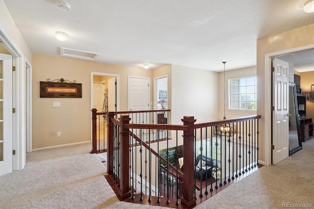 corridor with attic access, baseboards, an upstairs landing, and carpet