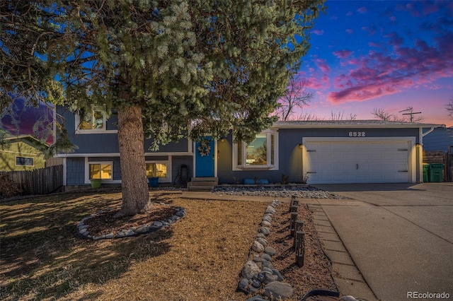 view of front of property featuring fence, a garage, and driveway