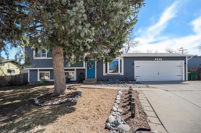 view of front of property with concrete driveway, an attached garage, and fence