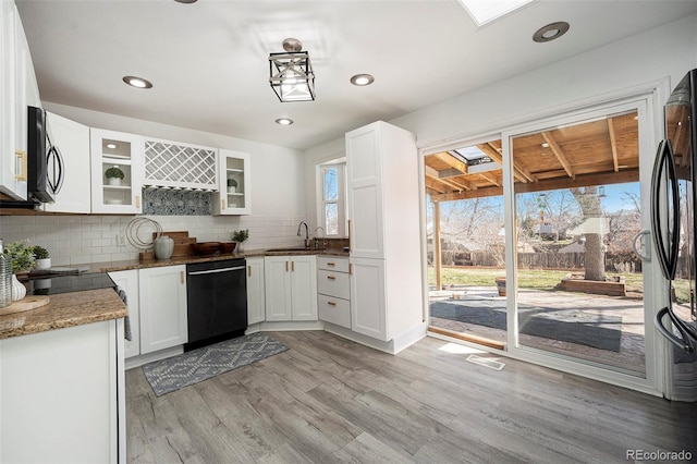 kitchen featuring a sink, light wood-type flooring, black appliances, and a wealth of natural light