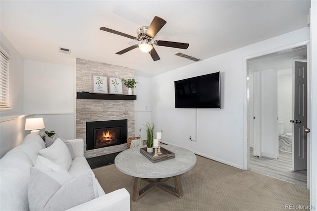 living area with a fireplace, visible vents, carpet floors, and ceiling fan