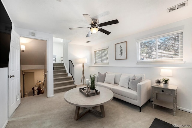 living room featuring stairs, visible vents, carpet floors, and ceiling fan