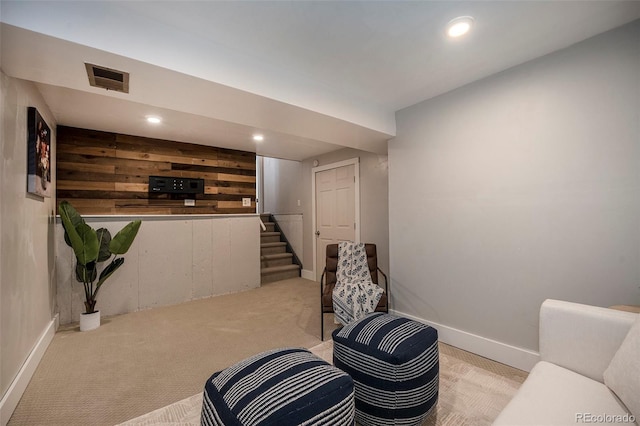 sitting room with visible vents, light carpet, recessed lighting, wood walls, and stairs