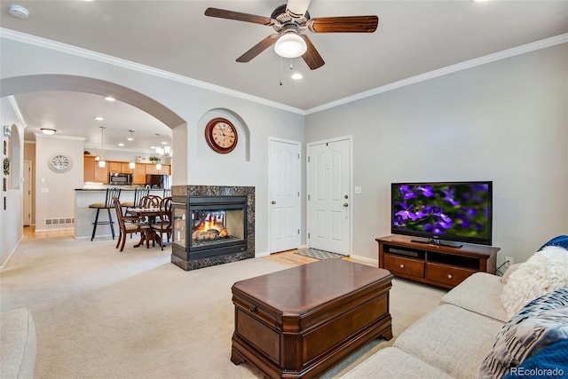 living area featuring ceiling fan, crown molding, arched walkways, baseboards, and recessed lighting
