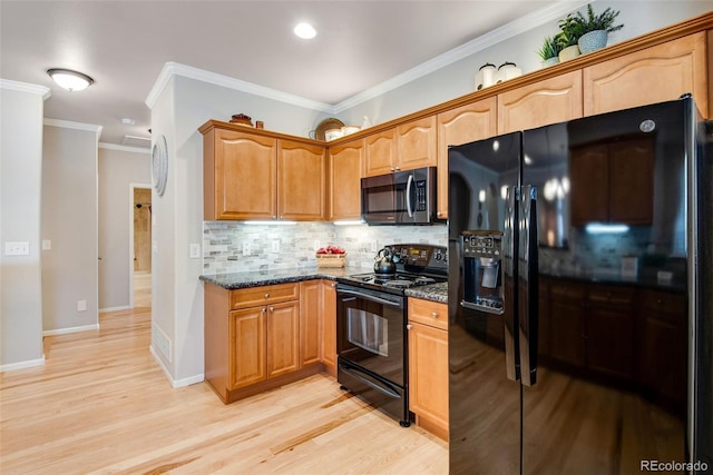 kitchen featuring dark stone counters, tasteful backsplash, black appliances, and light wood-style flooring