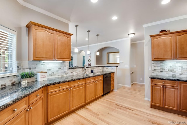 kitchen with a sink, dishwasher, arched walkways, dark stone counters, and decorative backsplash