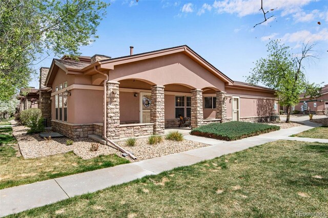 15501 E 112th Ave Unit 33D, Commerce City, CO 80022 - view of front of home featuring a porch, a front lawn, stone siding, and stucco siding